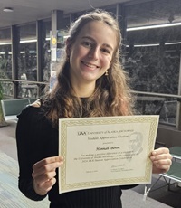 Woman in a black dress holding up a certificate.
