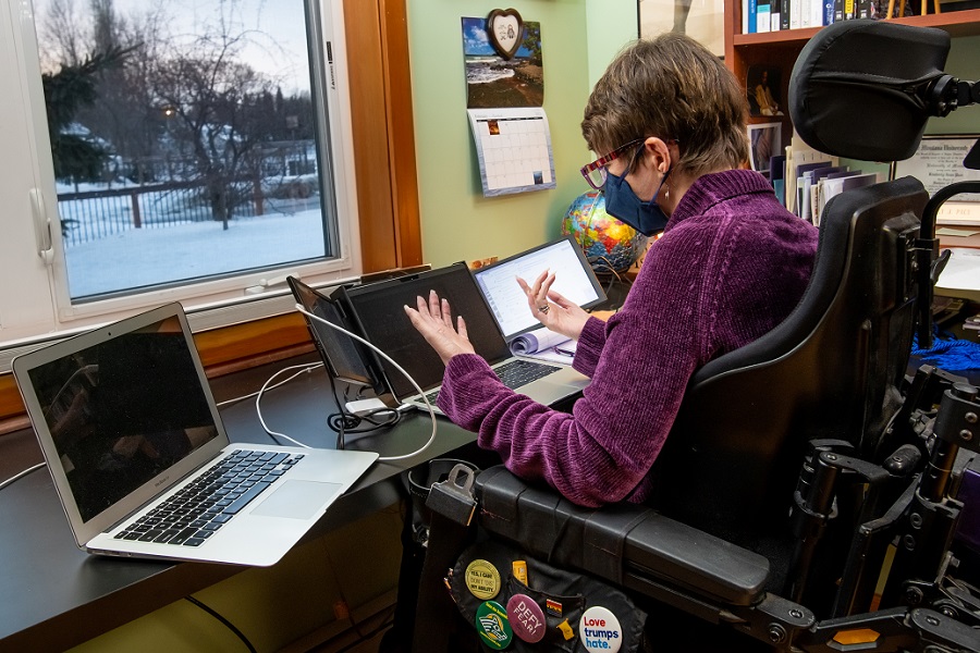instructor in a wheelchair at a desk with multiple monitors