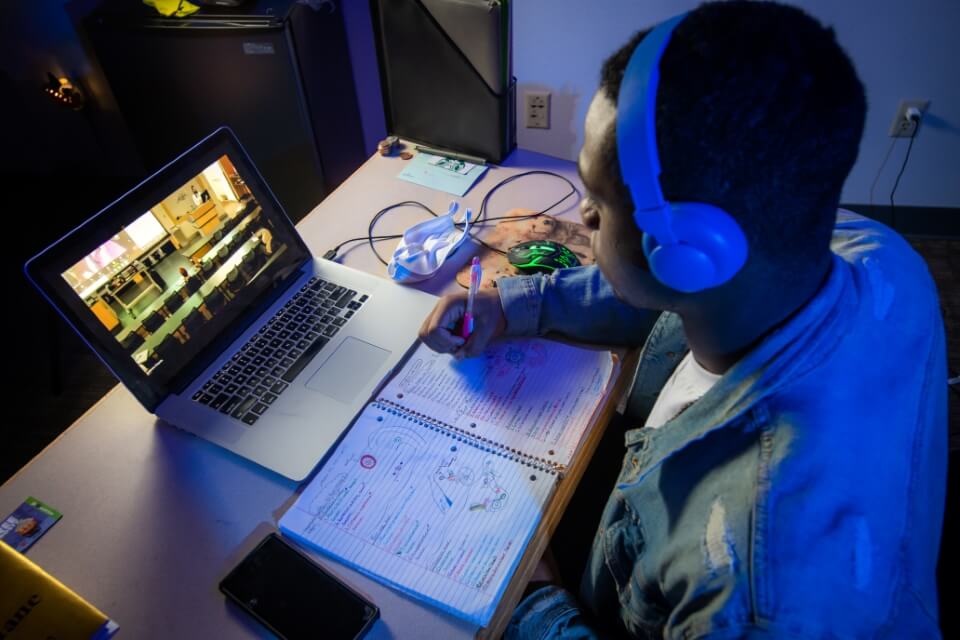 Student working on a laptop with headphones