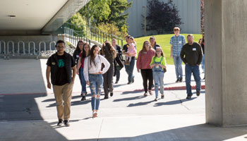 People follow a tour guide under the bridge between the Seawolf Sports Complex and Rasmuson Hall.