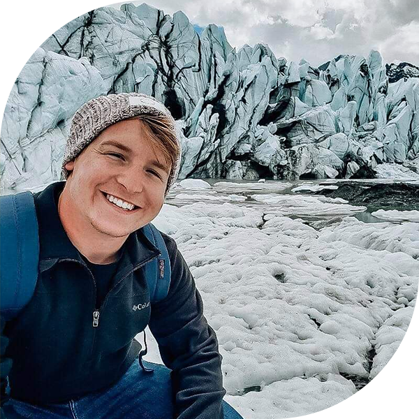 Admissions Counselor Justin Mahan smiling at camera and posing in front of a glacier.