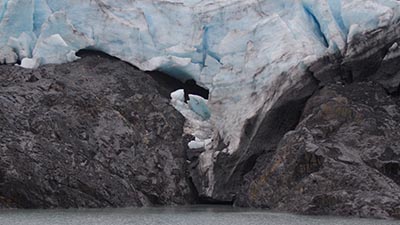 A glacier above rocks and water