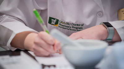A pharmacy student takes notes in the lab