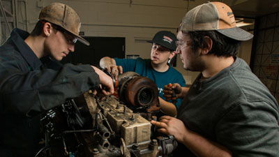 Automotive students working on an engine.