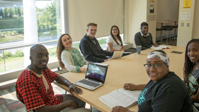 Students posing for the camera around a conference table