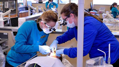 Two dental students working on a patient
