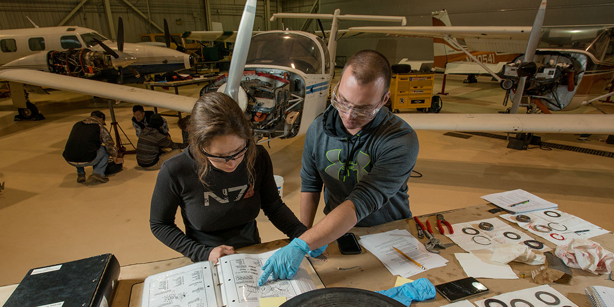 Two students looking at diagrams in an aircraft hanger