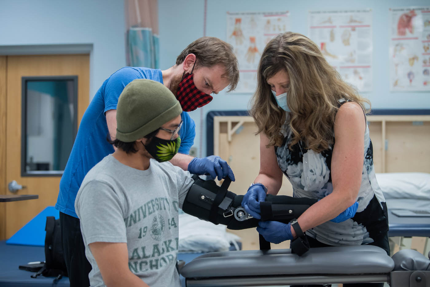 Two students assist a patient fit an arm brace