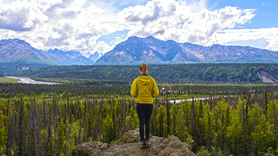 A student looking out on a vista with mountains in the background