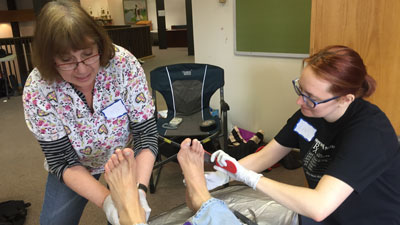 A teacher and a student working on a patient's foot