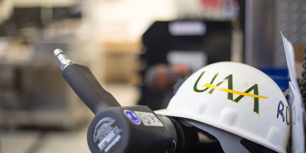 A UAA hardhat resting on a power tool.