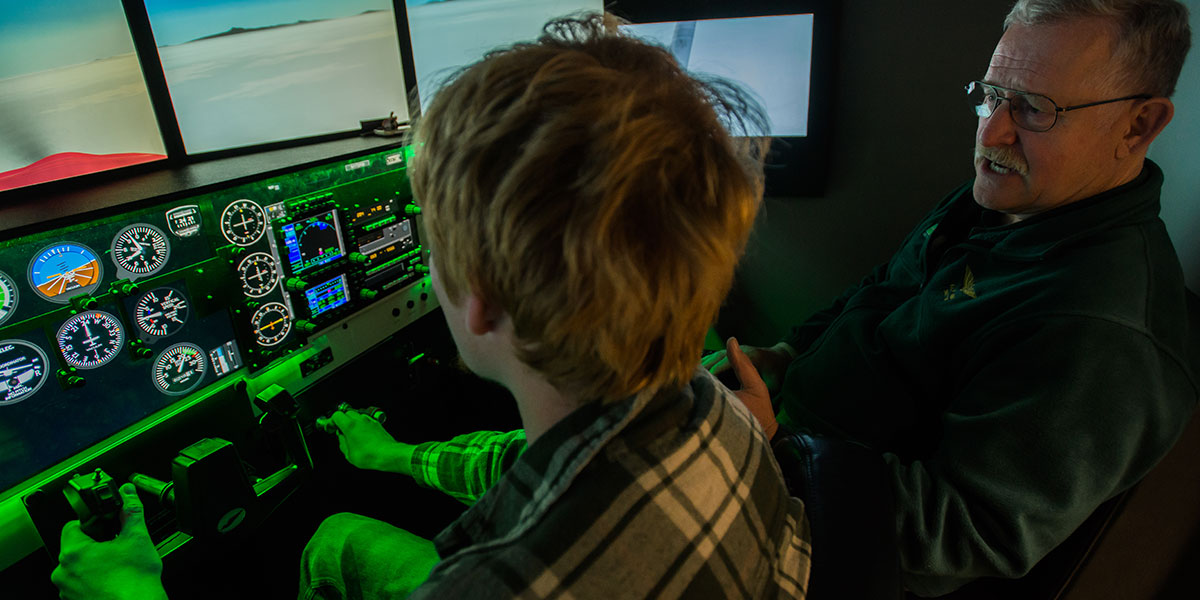 A student and instructor working inside a flight simulator