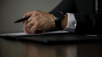 A hand with a watch holding a pen