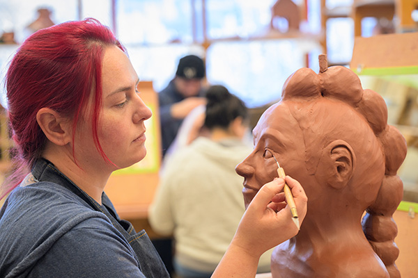 Haylie Travis works on her self portrait in clay project as Adjunct Professor of Art Lauren Stanford teaches Beginning Handbuilt Ceramics (ART A201) in UAA's Fine Arts Building.