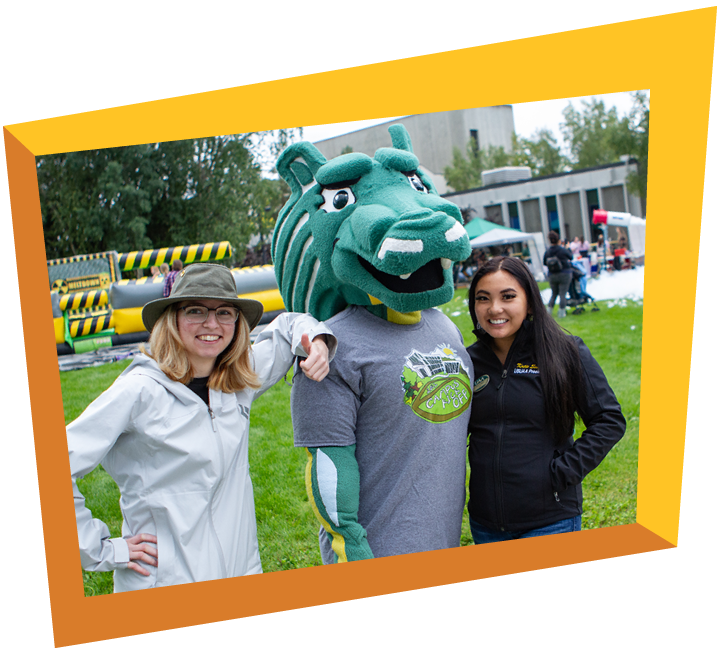 Two students posing with Spirit the mascot outside at Campus Kick Off.