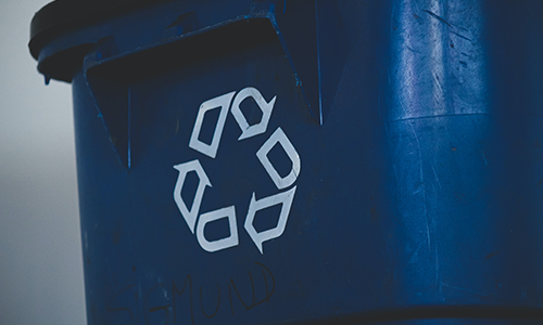 Blue recycling bin with recycling arrow sign on it.