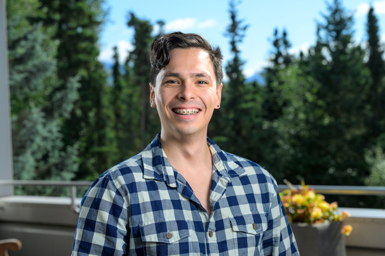 Male student in checkered shirt smiling to camera