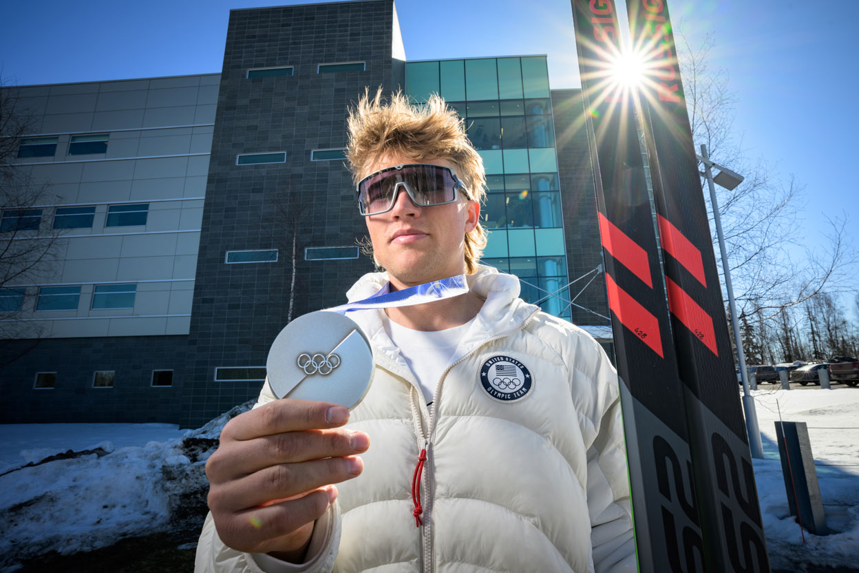 Man holding skis and silver Olympic medal