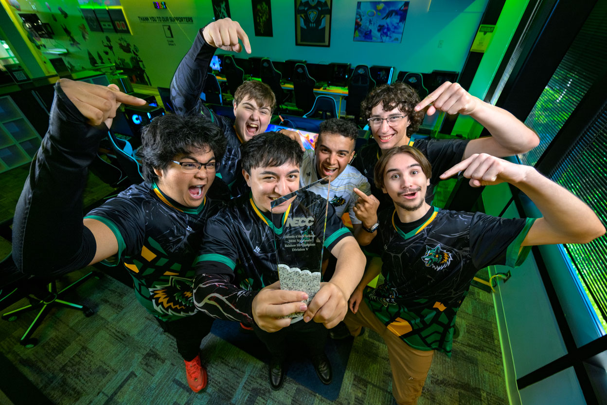 Six male students in jerseys holding glass trophy