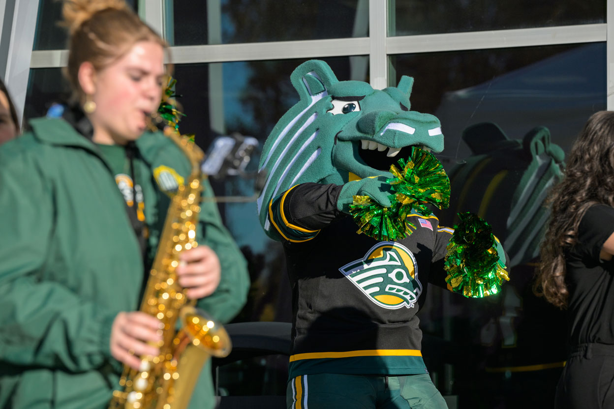 Spirit mascot shakes pom-poms next to saxophone player