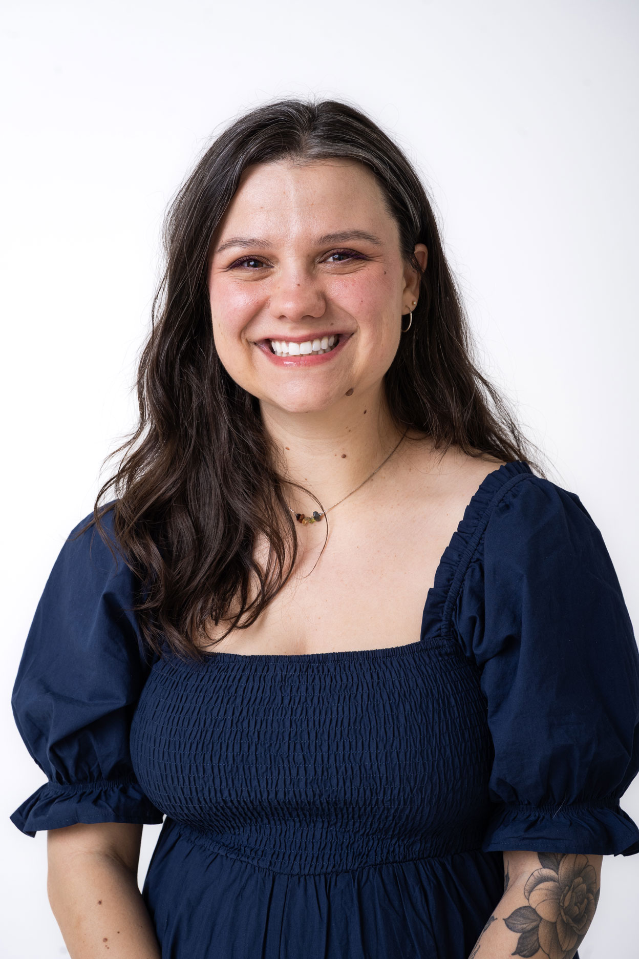 Smiling woman in blue dress in front of white background