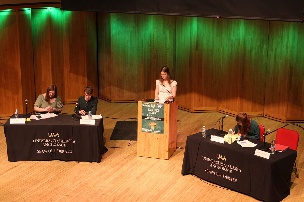 Four students debating on a stage