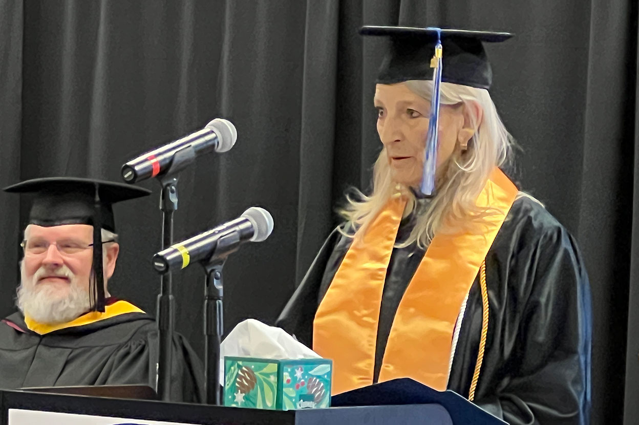 Woman in graduation gown delivering speech