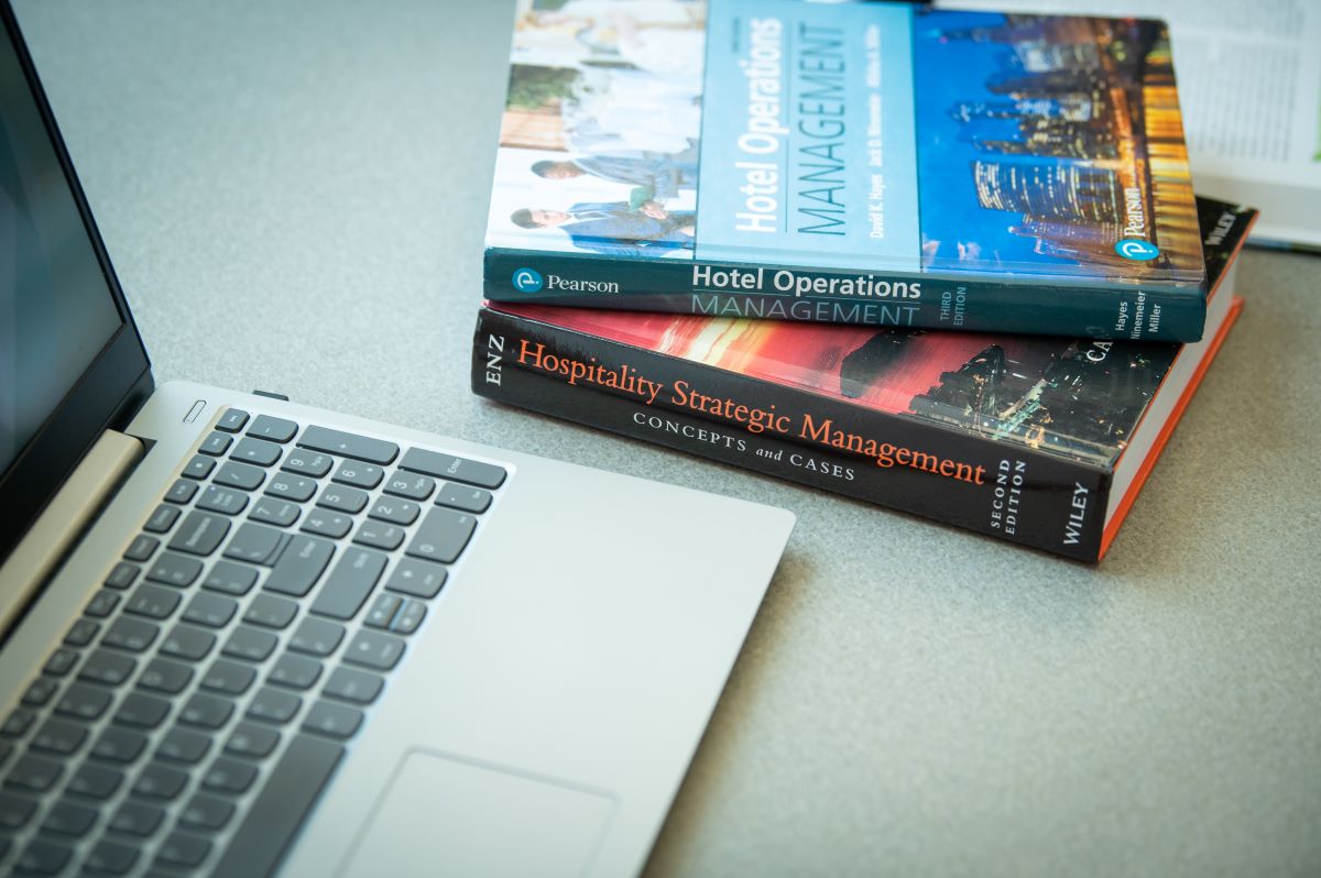 a laptop and two textbooks about hotel management
