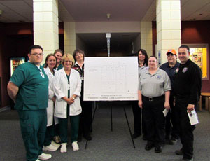 Associate Professor of Nursing Carol Nash and Assistant Professor of Paramedical Technology Kathy Griffin posing behind the floor plans, with their respective students, for the new expansion of Snodgrass Hall.