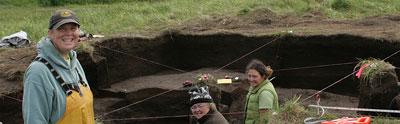 Dr. Diane Hanson, in yellow bibs, and UAA graduate student Roberta Gordaoff, in green vest, working a site on Adak 