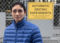 Joey Yang standing in front of the test sidewalk and deicing equipment.