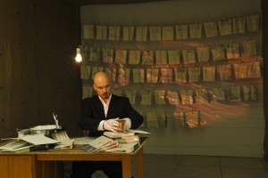 Vlad Basarab performing "The Censorship of Memory," video projection, pages ripped out of encyclopedias coated with clay slip, 2012.