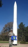 Capt. Amy Blanco proudly displays her UAA AFROTC Det001 flag next to the Minuteman III Missile on display at her current post, Vandenberg AFB in Lompoc, California.