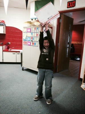 Angel holding up a package from UAA. Photo courtesy of Jordan Chacon/ Twombly Elementary School