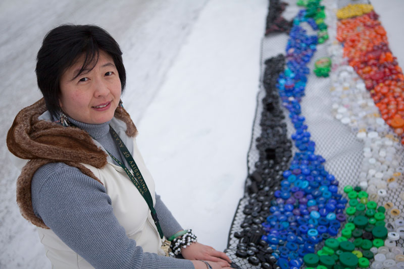 Herminia Din next to her "Flow of Color" Winter Design Project started in 2014 and continuing this year in the PSB Lobby. (Philip Hall/UAA)