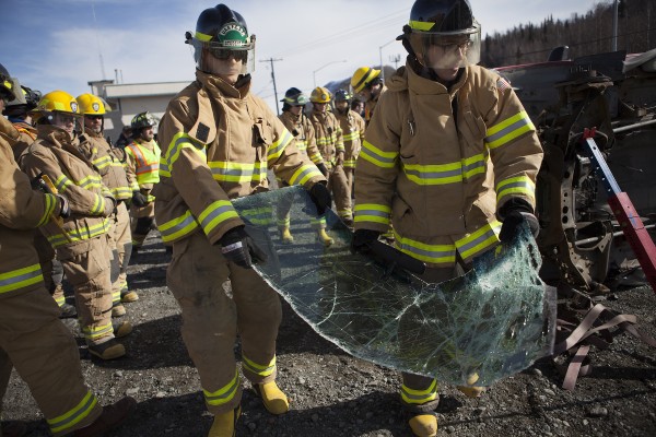 John Janezich (right) walks a sawed-off windshield away from the crash site (Photo by Philip Hall/University of Alaska Anchorage). 