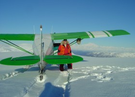 Mark's bush flying has taken him to temporary runways across the state, from gravel bars to frozen lakes to glaciers. Here he is with Denali in the background (Photo courtesy of Mark Madden).