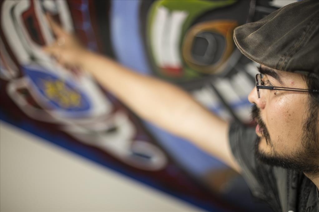 Student artist paints mural on Atrs building stairwell.