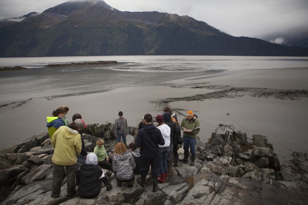 Dr. Kristine Crossen (seated, in green) teaches her students about glacial plucking from a "bathtub-"sized divot in the bedrock (Photo by Philip Hall / University of Alaska Anchorage).