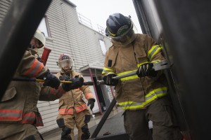 Tim, with the assistance of several full-time firefighters, busts through a steel door at the Wasilla training facility (Photo by Philip Hall / University of Alaska Anchorage).