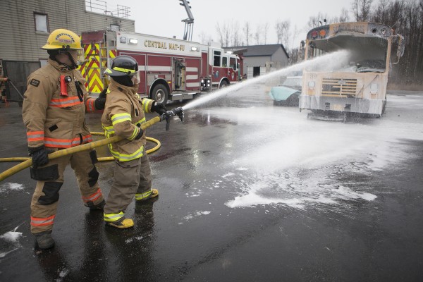 UAA fire and emergency services student Timothy Robbins hoses down a burned-out school bus during a training exercise at Central Mat-Su Fire Department in Wasilla (Photo by Philip Hall / University of Alaska Anchorage).
