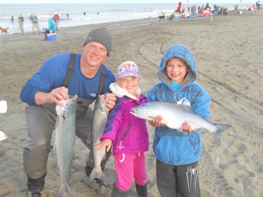 Mike Mueller with daughter Summer (5), and son Noah (8). He's holding sockeye salmon and Noah is holding a pink salmon the family caught while dipnetting at Kenai City Beach just north of Kenai River. (Photo provided by Mike Mueller/UAA)