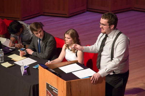 Sam Doepken stands at the podium while members of the proposition plot their counterarguments (Photo by Jacob Shercliffe, Seawolf Debate).