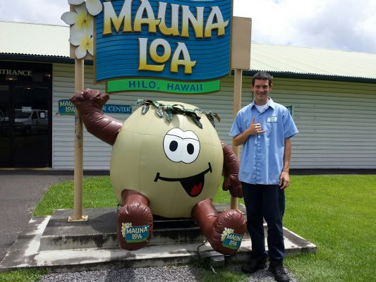 Aloha from Hawaii! Michael Karchere, B.B.A. management, global logistics management '06, throws up the shaka outside the Mauna Loa Macadmia Nut Corprotation, where he works as a purchasing manager (Image courtesy of Michael Karchere)