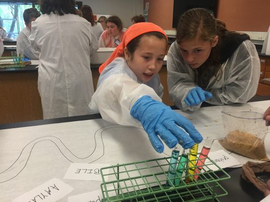 Randi Bunsen-Riffle, 11, left, and Mat-Su College student worker Kira Singleton take part in a simulated digestive system experiment during the campus' recent mini med school summer camp. (Photo by Tracy Kalytiak / University of Alaska Anchorage)