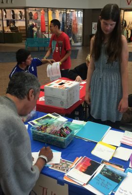 Isabel Trinborn, 17, watches a passer-by sign a card that will be sent to someone in the military. Isabel is enrolled in UAA's Tapestry program, helping kids with intellectual disabilities adapt to challenges they'll encounter in the workplace. (Photo by Tracy Kalytiak / UAA)
