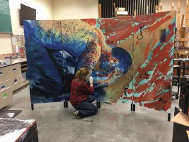 UAA art student Katherine Massong paints a portrait for the ACE's Mural Project.