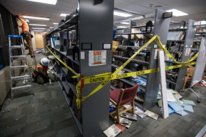 Subcontractors Trevor Todero and Steve Unfreid repair ceiling fixtures in the UAA Consortium Library exactly one week after a magnitude 7.1 earthquake shook the campus. We see library books and other debris on the floor from the quake.