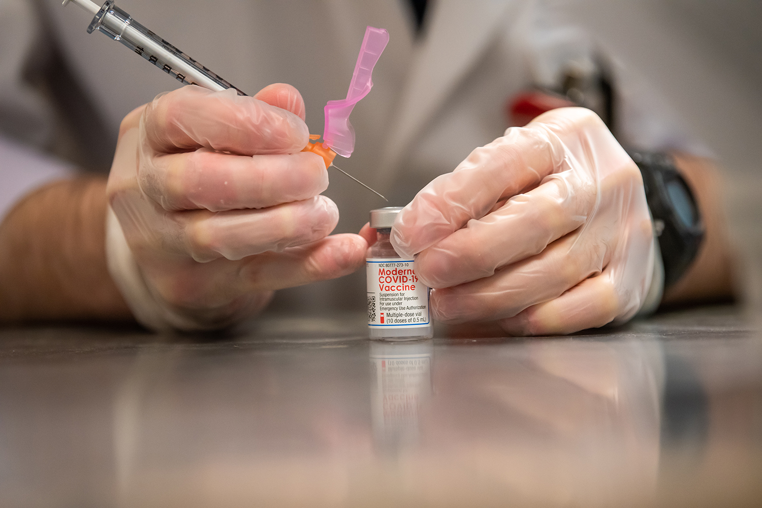 Close-up of a student's gloved hands as they prepare a COVID-19 vaccine.