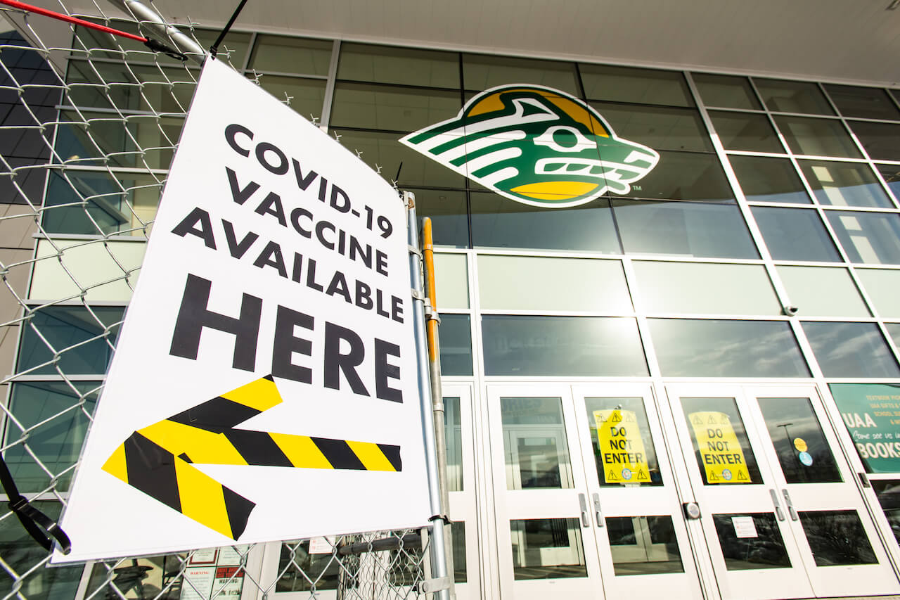 Signs outside UAA's Alaska Airlines Center pointing toward COVID-19 vaccine clinic.